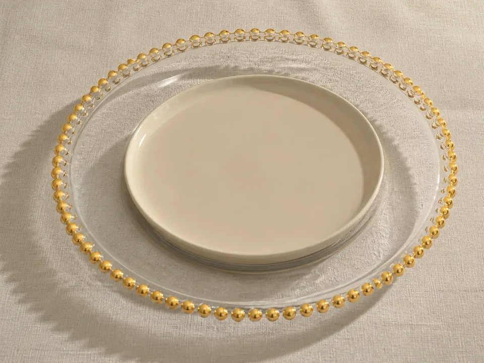 Bajo plato de cristal transparente con orilla dorada
