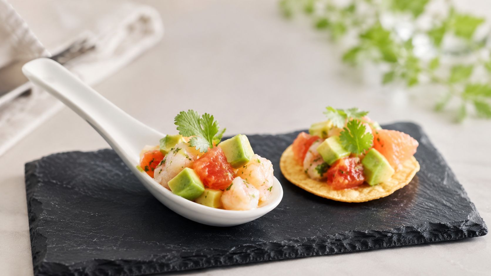 Una cuchara de degustación y una tostada pequeña con ceviche fresco de camarones, aguacate y pomelo.