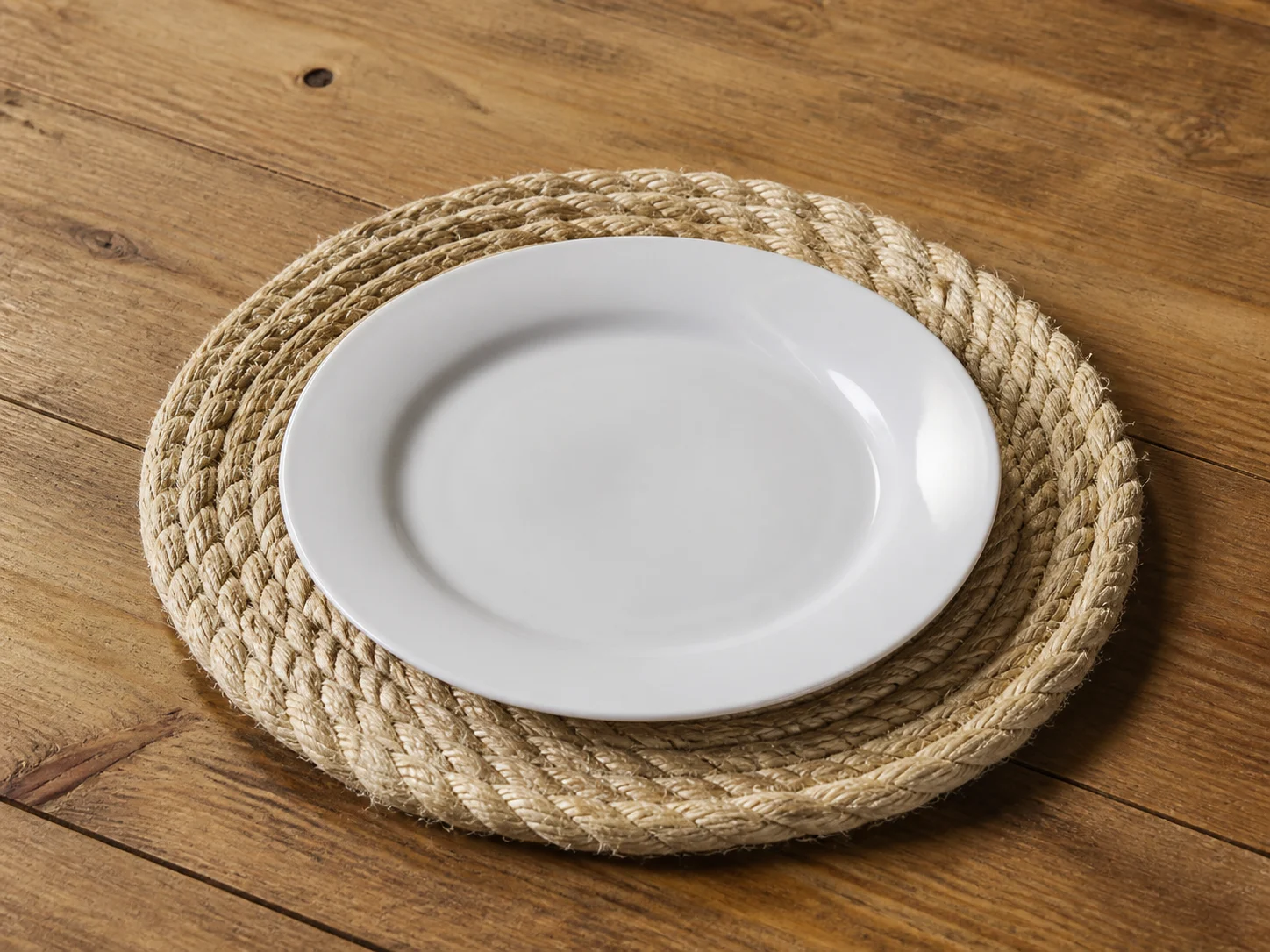 Bajo plato de fibra natural con plato blanco fotografiado en estudio