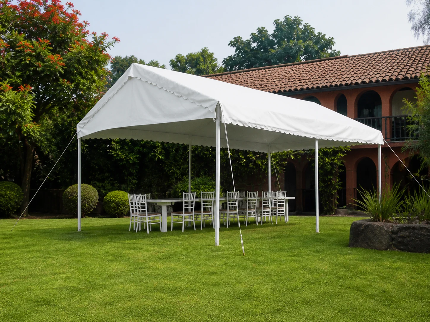 Carpa tradicional blanca instalada con mobiliario en jardín